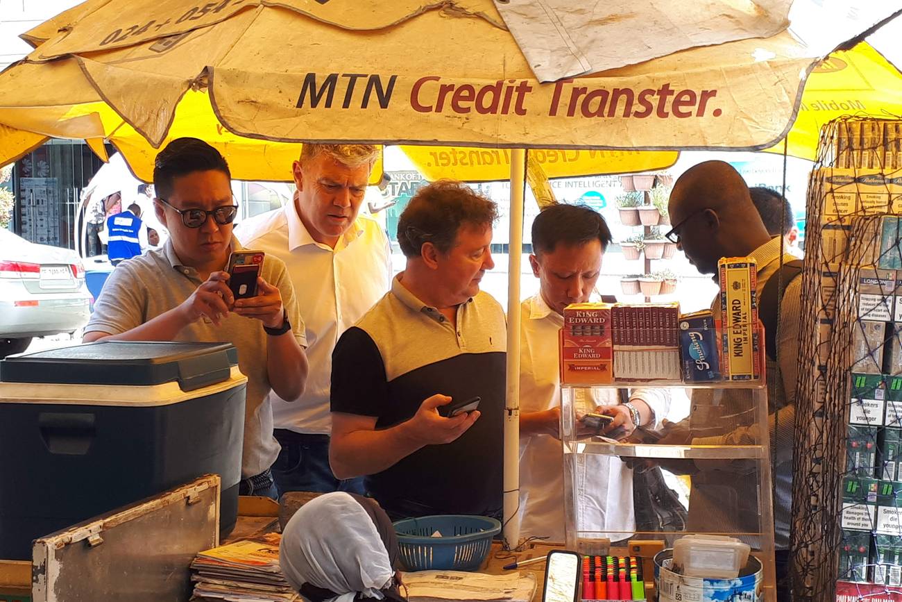 An investor team testing mobile money at a street kiosk in Accra